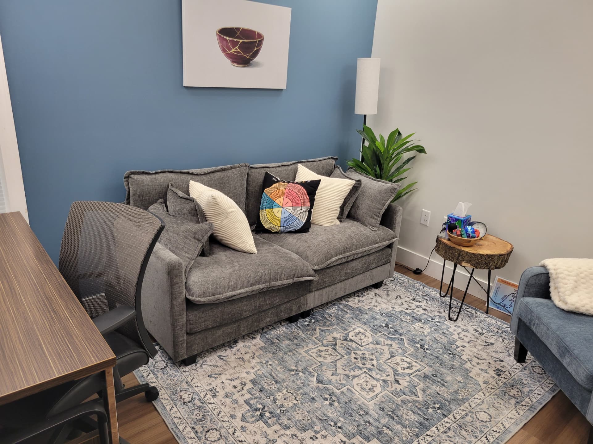 The therapy office: a comfortable grey couch and warm, welcoming space